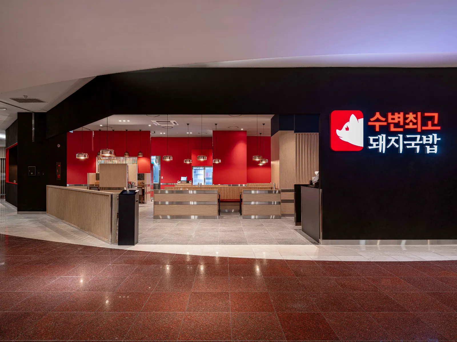 붉은 벽과 원목 테이블이 보이는 수변최고돼지국밥 매장 입구와 간판